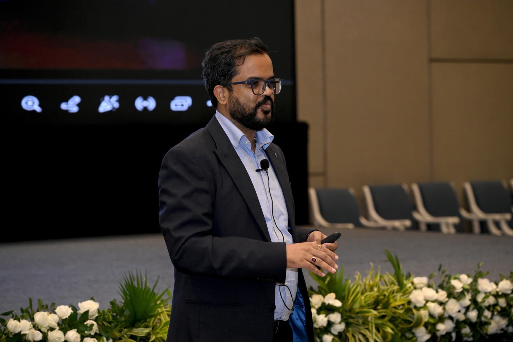 Amit Kumar Soni presenting on a stage with a clicker, white flowers in the foreground.