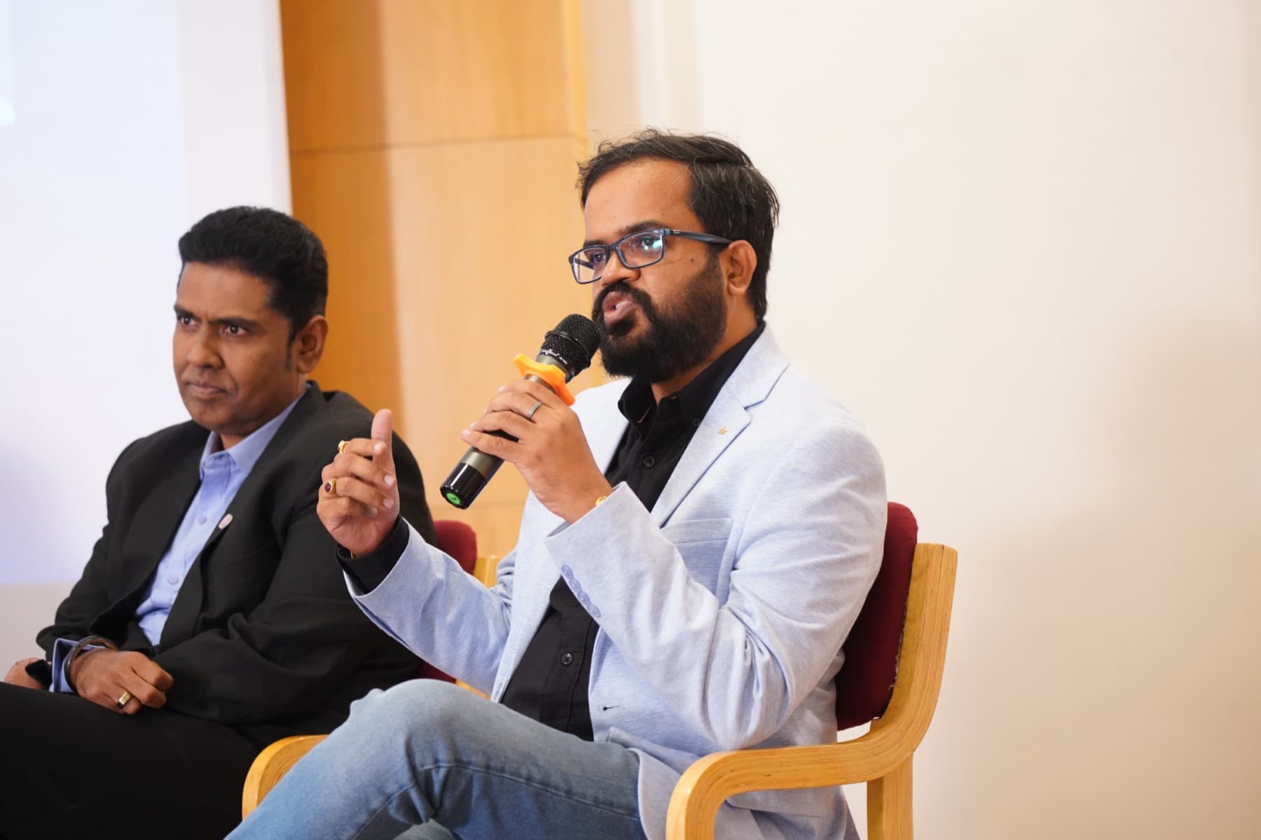 Amit Kumar Soni making a point with a microphone during a panel discussion.