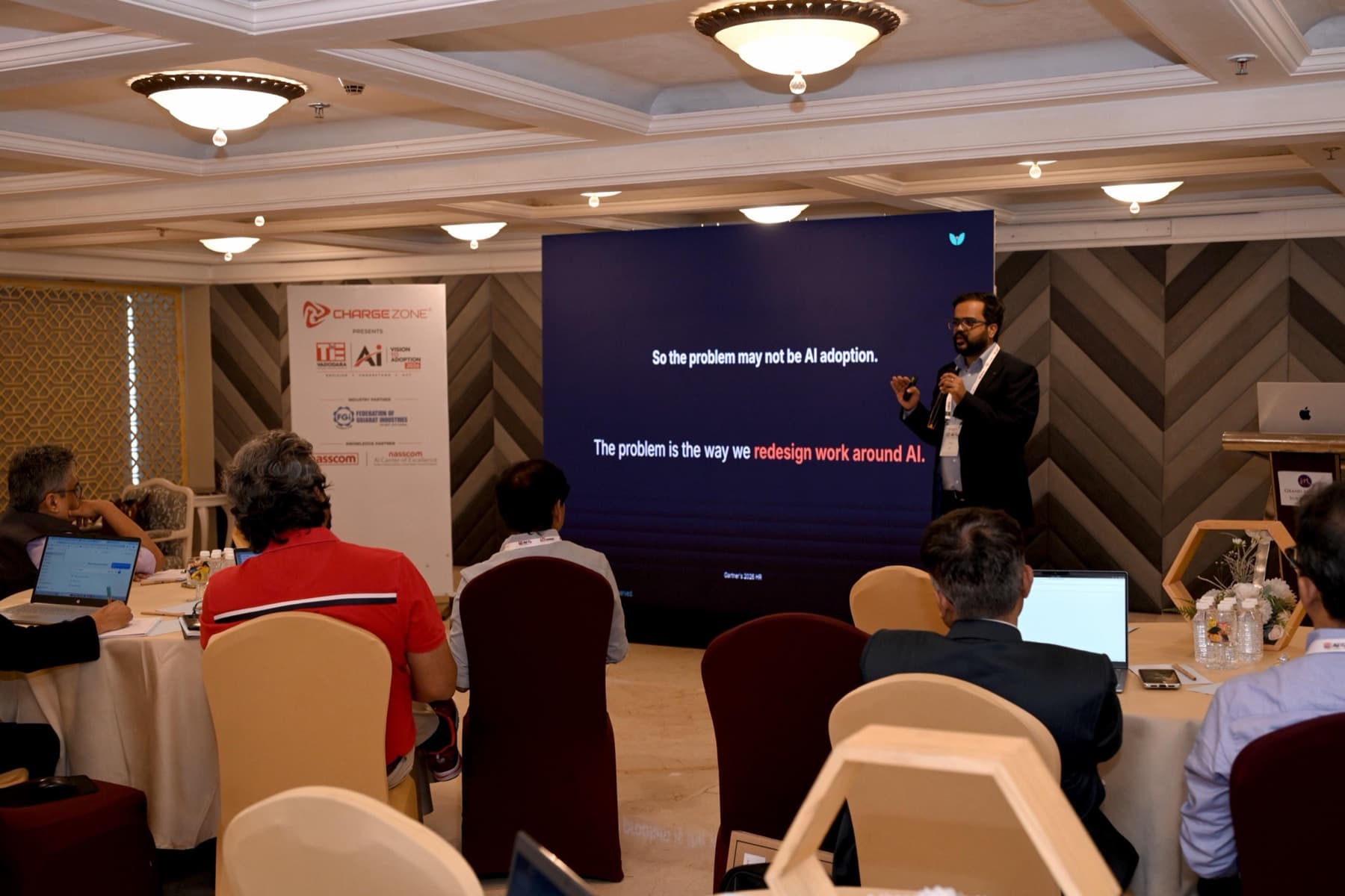 Amit Kumar Soni speaking beside a screen reading that the problem is how we redesign work around AI.
